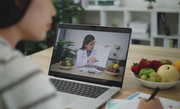 Woman taking notes while in a telenutrition session with a dietitian