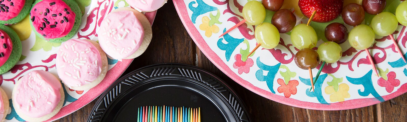 Cookies and fruits on colorful paper plates